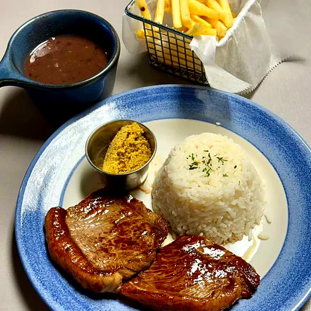 Dois bifes grelhados com arroz, farofa e feijão no restaurante Sabor Brasil